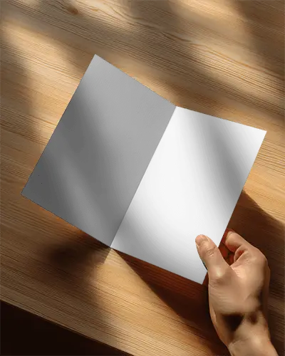 Hand Holding Minimalist Bifold Brochure On Wooden Surface With Natural Light Shadows