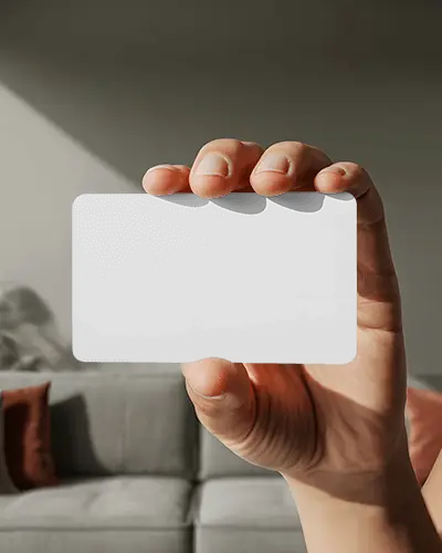 hand-holding-horizontal-business-card-mockup-floating-over-sofa-background-in-natural-light
