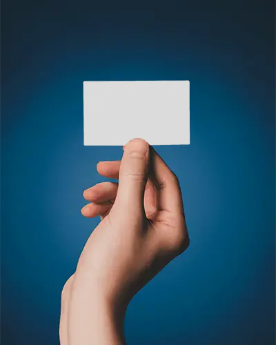 Hand Holding Blank Business Card Mockup Against Solid Background For Design Presentation