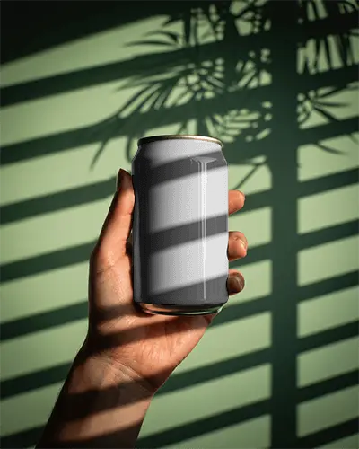Tropical Shadow Can Mockup Hand Holding Drink With Leaf Patterns On Green Wall