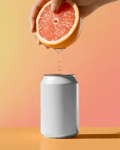 Citrus Drip Can Mockup Hand Holding Fruit Above Can Gradient Background Bright Refreshing Scene