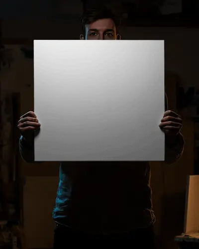 Blank Canvas Mockup Held By Artist Against Dark Studio Background For Design
