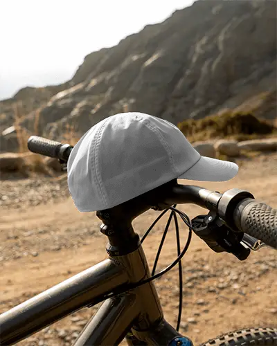 Outdoor Trail Cycling Cap Mockup Resting On Bike Handlebar With Rocky Mountain Scenic Backdrop