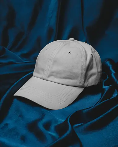 Satin Drape Cap Mockup Baseball Hat Placed On Dark Blue Fabric Smooth Elegant Background