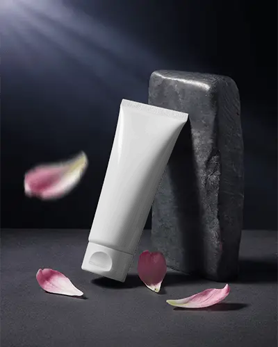 Elegant Skincare Tube Mockup Set Against Dark Stone With Delicate Petal Decoration