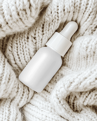 dropper-bottle-mockup-cozy-matte-frosted-container-nestled-in-soft-knitted-blanket-warm-and-inviting-textured-aesthetic-087