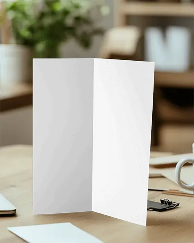 Cozy Office Brochure Mockup Trifold Standing On Wooden Desk With Mug And Stationery Blurred Greenery Background Warm And Professional Setting 058