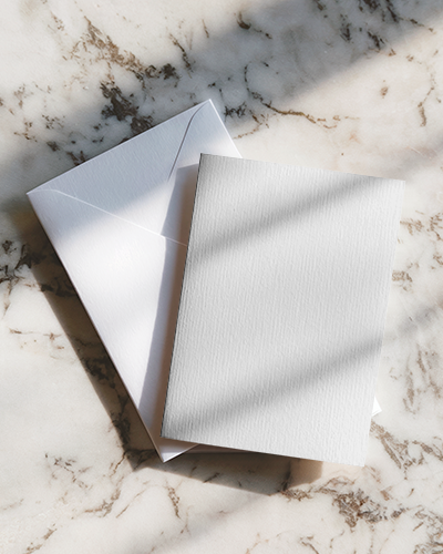 Sunlit Greeting Card Mockup On Marble Surface With Envelope Soft Shadows And Textured Paper In Natural Light
