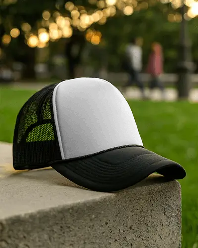Trucker Hat Mockup Placed On Concrete Surface With Park Background And Soft Golden Hour Bokeh Effect