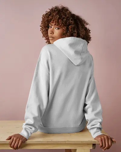 Back View Hoodie Mockup With Female Model Sitting On Wooden Table Against Soft Pink Background