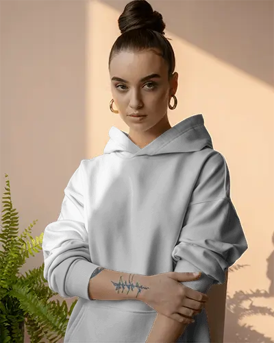 Sunlit Interior Hoodie Mockup Female Model With Top Bun And Arm Tattoo Standing By Plant In Warm Studio Light 0598