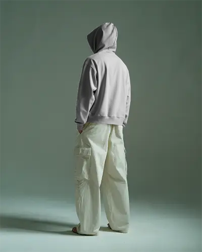 Moody White Hoodie Mockup Back View Man In Cargo Pants Hood Up Hands In Pockets Green Background Soft Shadow Design On Back