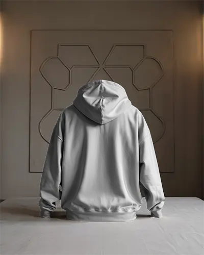 Minimalist Indoor Hoodie Mockup Back View Model Kneeling On White Table Against Geometric Wall Art