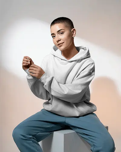 Relaxed Fit Hoodie Mockup Featuring Buzzcut Model In Seated Pose With Minimal Studio Lighting For Bold Brand Identity