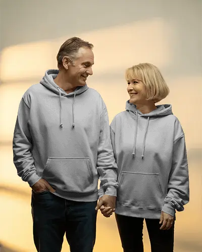 Warm Lit Hoodie Mockup Senior Couple Holding Hands Smiling In Studio Setting
