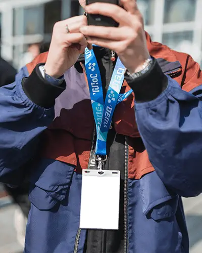 Stylish Id Card Mockup At Public Gathering Showing Pass Design For Event Or Festival Hanging On Lanyard Worn By Person Taking Pictures During Busy Outdoor Afternoon