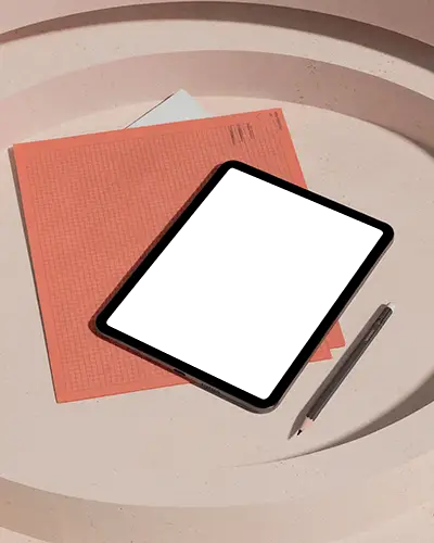 Ipad Mini Mockup Flatlay On Round Beige Tabletop With Orange Graph Sheet And Pencil Stationery