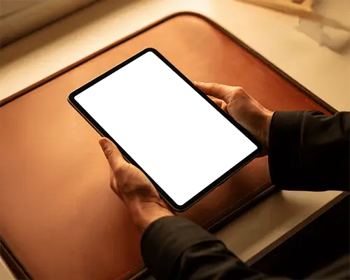 Ipad Pro Mockup Hands Holding Tablet Over Leather Desk In Warm Office Lighting