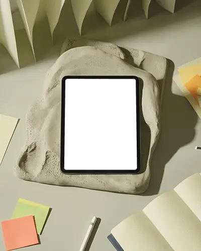 Artistic Ipad Air Mockup Embedded In Stone Texture With Open Notebooks And Stationery Around