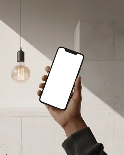 Hand Holding Iphone 13 Mockup Under Warm Lightbulb With Minimal Stone Wall Background