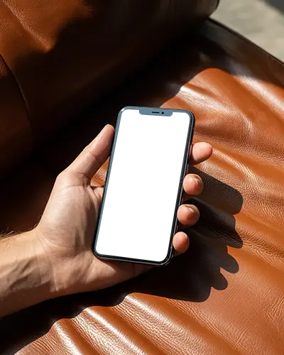 Hand Holding Iphone 12 Mockup On Leather Couch For Creative Usage