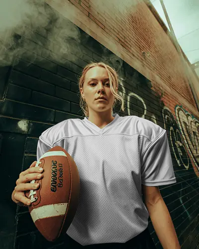 Urban Football Jersey Mockup Female Player Holding Ball In Smoky Alleyway