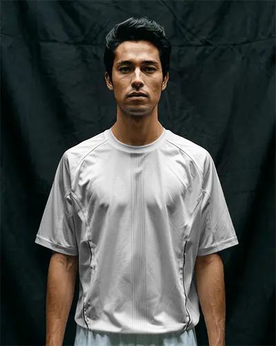 football-jersey-mockup-male-model-standing-against-dark-cloth-backdrop-straight-posture-minimal-light-athletic-fit-showcase