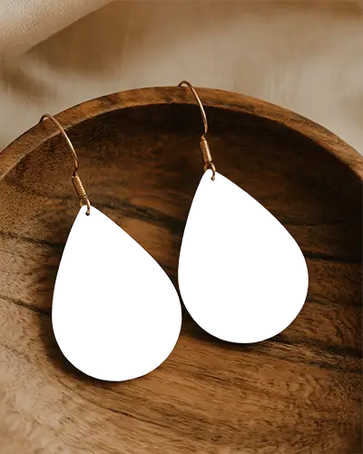 Elegant Black Teardrop Earrings Hanging On Golden Hooks Sitting On Wooden Bowl With Soft Lighting