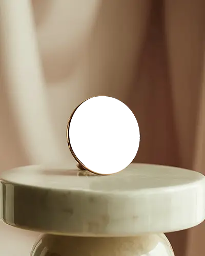 Minimalistic Round Black Earring Resting On White Marble Table With Soft Light