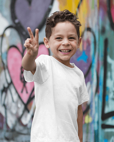Vibrant Street Style Kid T Shirt Mockup Smiling Boy In Bright Red Tee With Sneaker Graphic Posing Against Colorful Graffiti Wall Playful And Urban Look