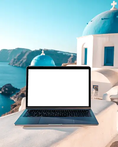 macbook-pro-m1-mockup-on-white-terrace-overlooking-blue-domes-and-aegean-sea-in-santorini
