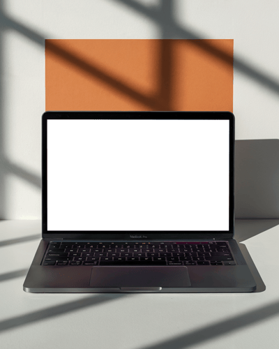 Macbook Pro M1 On Vintage Chair Surrounded By Stacked Books With Soft Sunlight Creating An Inviting And Cozy Ambiance
