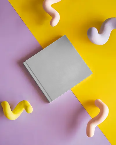 Flat Lay Hardcover Magazine Mockup On Dual Tone Yellow And Lilac Background With Colorful Abstract Clay Shapes Creative Studio Setup 0307