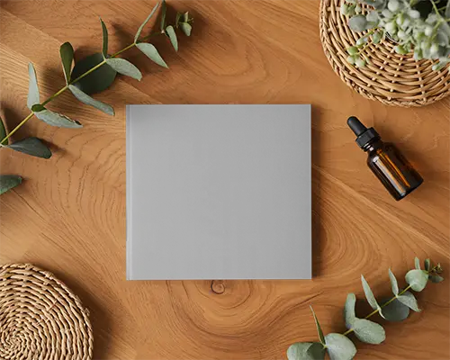 Square Magazine Mockup On Natural Wood Background With Greenery And Dropper Bottle