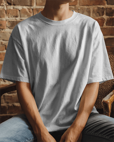 Urban Casual T Shirt Mockup Man Wearing Loose Shirt Relaxed Casual Sitting In Chair With Brick Wall Background