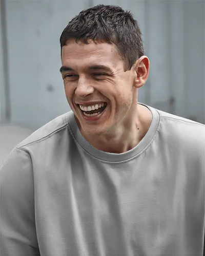 Urban Closeup Front View T Shirt Mockup Smiling Male Model In Boxy Grey Tee Natural Light Candid And Modern Streetwear Vibe