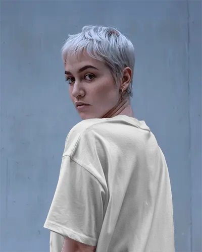 White Back Print Tshirt Mockup Short Haired Female Model Looking Over Shoulder Blue Wall Background Template