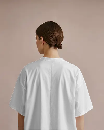 Back View Tshirt Mockup Female Model With Low Bun On Soft Beige Backdrop Clean White Fabric And Relaxed Fit Style