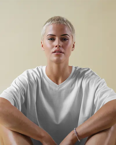 Minimal T Shirt Mockup Female Model In Relaxed White Tee Sitting Against Soft Beige Wall Casual And Confident Look