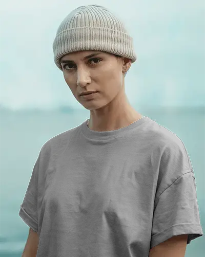 Outdoor Streetwear T Shirt Mockup Female Model Wearing Grey Tee And Beanie Staring Seriously With Light Blue Background