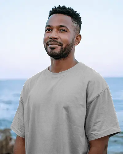 Outdoor T Shirt Mockup Smiling Male Model In Grey Tee Facing Camera With Ocean Horizon And Natural Light