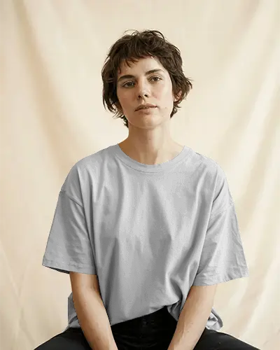 Calm And Minimalist Tshirt Mockup On Woman Sitting In Relaxed Pose Against Beige Curtain Backdrop