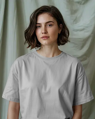 Indoor T Shirt Mockup Female Model With Wavy Bob Hair Wearing Grey Tee In Front Of Soft Draped Curtain Backdrop