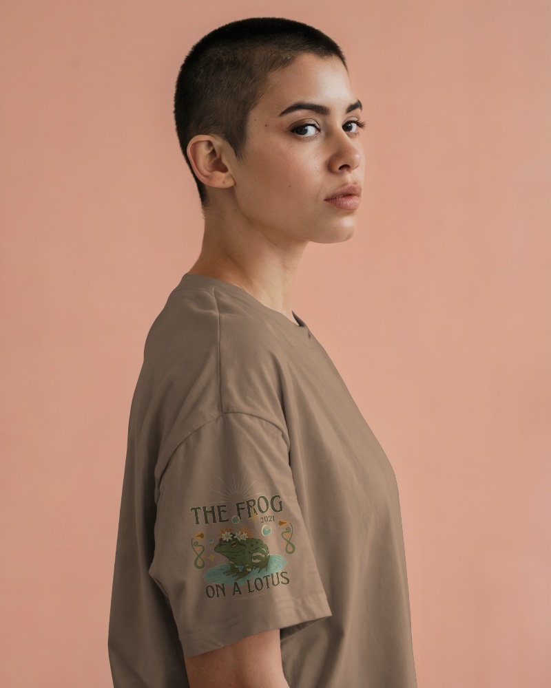 Studio T Shirt Mockup Female Model With Buzzcut Showing Sleeve Design On Grey Tee Against Soft Peach Backdrop
