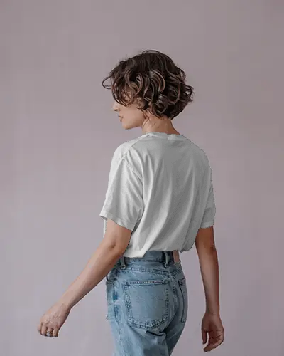 Pastel Studio T Shirt Mockup Female Model In Light Denim Turning Sideways Back View Focus
