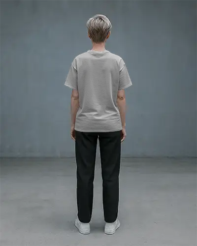 Back View T Shirt Mockup Female Model In Light Grey Tee Standing Straight On Concrete Floor Minimal Studio Background Clean Rear Design Showcase