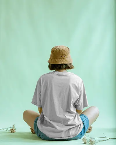 Minimal Studio T Shirt Mockup Back View Female Model Sitting On Floor With Beige Bucket Hat And Calm Aura