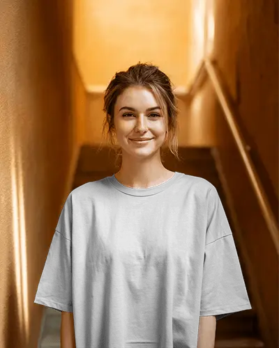 Sunlit Urban T Shirt Mockup Female Model Smiling In Casual White Oversized Tee Soft Warm Lighting Against Textured Stairway Background