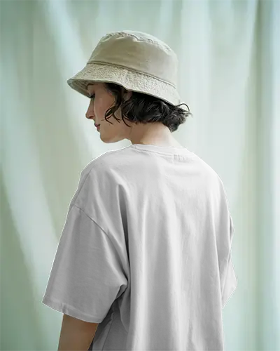 Back View Tshirt Mockup Woman Wearing Beige Bucket Hat Minimal White Tee Soft Green Fabric Backdrop Perfect For Nature Inspired Design Showcase