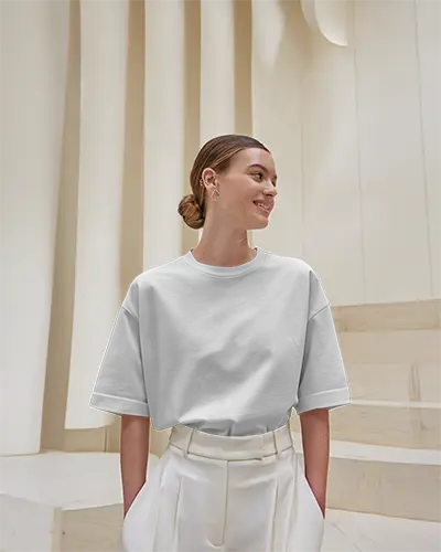 Minimalist Architectural T Shirt Mockup Woman Smiling In Softly Lit Modern Interior Wearing White Tee With Rolled Sleeves High Waist Trousers
